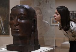 A photo of a woman looking at a sculpture of a head